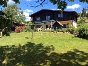 a house on a hill with a green yard at Chalet Les Chardons in Gérardmer