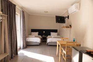 a hotel room with two beds and a table and a television at One One Five Albrecht Street in Bloemfontein