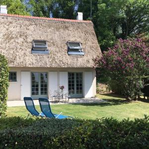 two blue chairs sitting in the grass in front of a house at Le Lodge des Prés in Eu