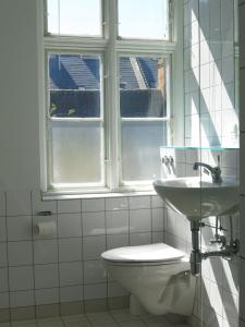a bathroom with a toilet and a sink and two windows at ApartmentInCopenhagen Apartment 1144 in Copenhagen