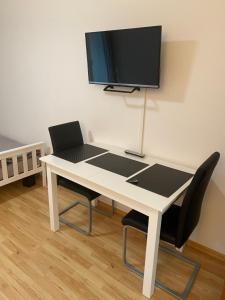 einen weißen Tisch mit 2 Stühlen und einen TV an der Wand in der Unterkunft 1 Zimmer City Appartement mit Balkon in Göttingen