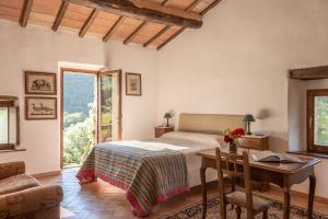 Bed and Breakfast Le Pianore في Cinigiano: غرفة نوم بسرير ومكتب وطاولة