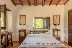 Bed and Breakfast Le Pianore في Cinigiano: غرفة نوم بسرير وطاولتين ونافذة