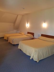 a row of three beds in a room at Hotel les forges in Noyal-sur-Vilaine