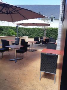 een groep tafels en stoelen met parasols bij Hotel les forges in Noyal-sur-Vilaine