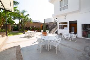 a patio with white tables and chairs and a building at Hotel Villas De San Miguel Media Luna in Río Verde