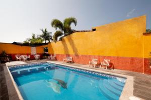 a swimming pool in front of a building with chairs at Hotel Villas De San Miguel Media Luna in Río Verde