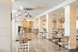 - un restaurant avec des tables et des chaises dans une salle dans l'établissement Hotel Indalo Park, à Santa Susanna