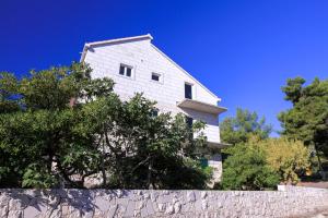 una casa bianca dietro un muro di pietra e alberi di Studio Ruzmarin a Selca