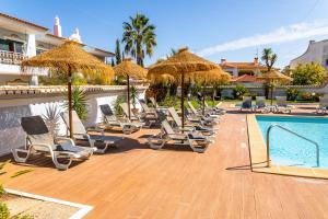 a bunch of lounge chairs and a swimming pool at Giramar Apartamentos Turisticos in Lagos