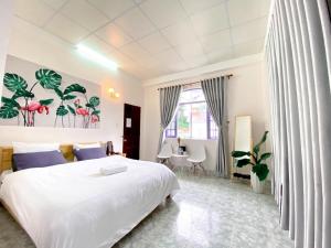 a bedroom with a large white bed and a table at HOMESTAY THÙY DƯƠNG in Da Lat