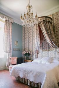 a bedroom with a large bed with a chandelier at Chateau de Varenne in Sauveterre