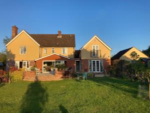 una gran casa amarilla con patio en Newmans Lodge, en Lavenham