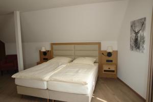 a bedroom with a large bed with white sheets at Hotel Kallstadter Hof in Kallstadt