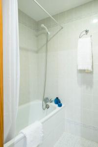 y baño blanco con ducha y bañera. en Magalluf Strip Apartment, en Magaluf