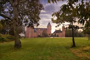 a large castle with a grass field and trees at Stayokay Hostel Domburg - Fully renovated per February 2023 in Oostkapelle