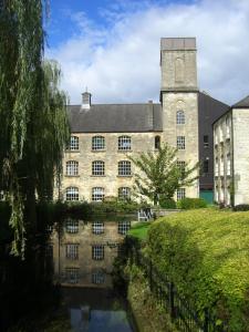 a large stone building with a river in front of it at Cotswolds Valleys Accommodation - Bell Apartments - Exclusive use large two bedroom family holiday apartment in Stroud