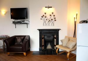 a living room with a fireplace and two chairs and a tv at Cotswolds Valleys Accommodation - Bell Apartments - Exclusive use large two bedroom family holiday apartment in Stroud