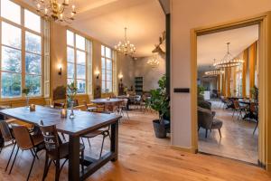 Un comedor con mesas y sillas y ventanas. en Stayokay Hostel Domburg, en Oostkapelle