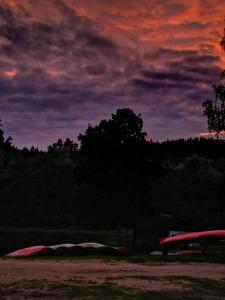 a sunset over a field with tents and trees at Kempings Ozolkalns in Cēsis