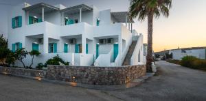 a white building with chairs and a palm tree at Michalis Studios in Pollonia