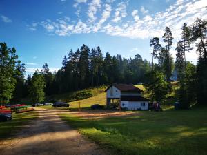 a house on the side of a field with a dirt road at Kempings Ozolkalns in Cēsis