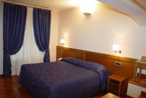 a bedroom with a blue bed and blue curtains at Hotel Iris in Genoa