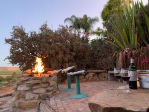 a fire pit with two glasses of wine and a table at Melkboomsdrift Guest House & Conference Centre in Vredendal