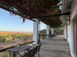 uma mesa e cadeiras num alpendre com vista em Melkboomsdrift Guest House & Conference Centre em Vredendal