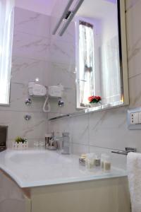 uma casa de banho branca com um lavatório e um espelho em Elegance B&B em Nápoles