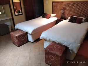 a hotel room with two beds and a suitcase at Hanlin Lodge in Modimolle