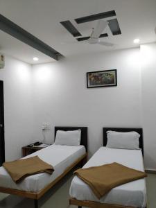 two beds in a room with white walls at Hotel neptune in Amreli