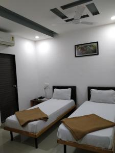 two beds in a room with white walls at Hotel neptune in Amreli +7 photos