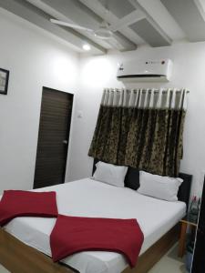 a bedroom with a bed with a red and white blanket at Hotel neptune in Amreli