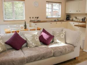 um sofá branco com almofadas na cozinha em Alder River Lodge Clun Valley Luxury Hot Tub Break em Craven Arms