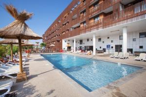 uma piscina com cadeiras e um hotel em Résidence Odalys Terra Gaia em Sète