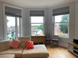 een woonkamer met een bank en 3 ramen bij Sea view newly refurbished flat in Parkstone
