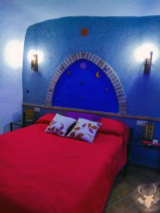 1 dormitorio con cama roja y pared azul en Cueva Arroyo Molino - CuevasCazorla, en Hinojares