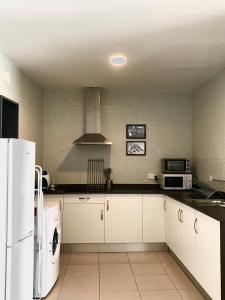 a kitchen with white cabinets and a white refrigerator at Apartamentos Élite - Art Collection - Pablo in Merida