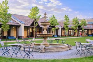 a fountain in front of a building with tables and chairs at Manufactura Design-Hotel in Khodosovka