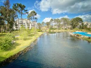 a river in a park with buildings in the background at Green Park Solanas Departamento en PB con Jardín y Parrillero in Punta del Este