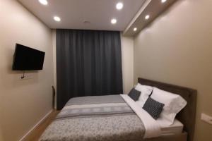 sypialnia z łóżkiem z poduszkami i telewizorem w obiekcie Apartamentai Giluzes Rivjera w Wilnie