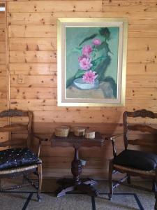 una pintura de un jarrón de flores en una mesa con dos sillas en Cruz del Sur en Pinamar