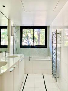 a white bathroom with a tub and a sink at Carlton Riviera in Cannes
