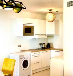 カンヌにあるCarlton Rivieraのキッチン(白いキャビネット、洗濯機、乾燥機付)