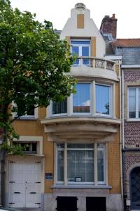 een huis met witte deuren en een boom bij Gite l'Escale Malo in Duinkerke