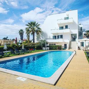 a swimming pool in front of a house at Debimar Apartamentos in Albufeira