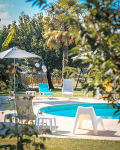 a swimming pool with chairs and an umbrella next to it at Hotel de Charme Casa Fundevila in Vila Verde