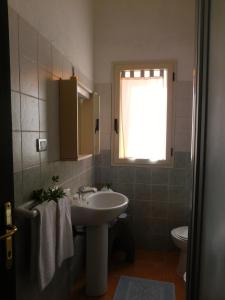 a bathroom with a sink and a toilet and a window at Residence La Pineta in Budoni