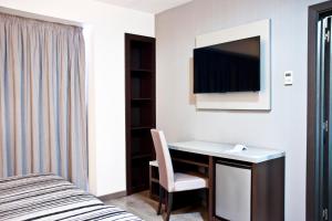 a bedroom with a desk with a chair and a tv at Summer Hotel in Calella